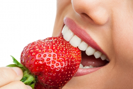 Macro close up of woman's mouth eating strawberry.の写真素材