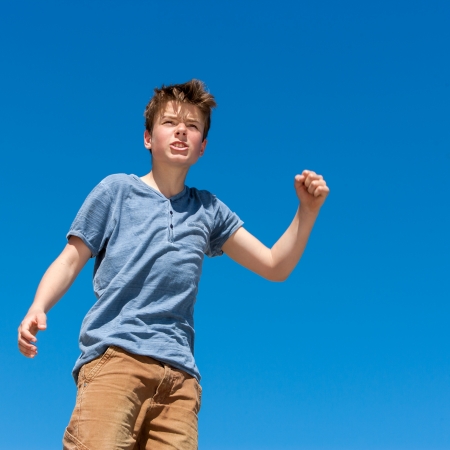 Close up portrait of upset boy raising fist outdoors.の写真素材