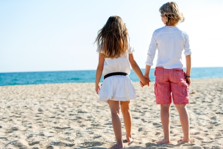 Cute boy and girl holding hands looking at sea.の写真素材