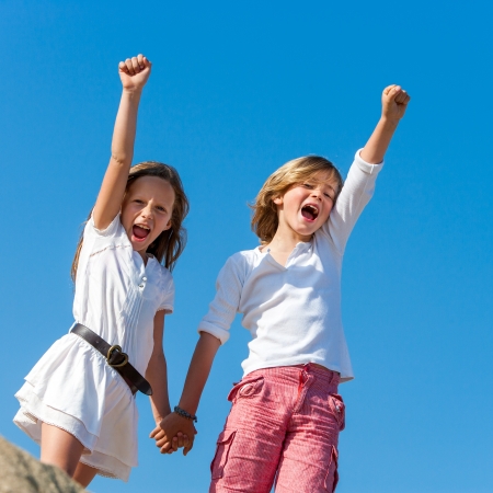 Two kids shouting and raising hands outdoors,の写真素材