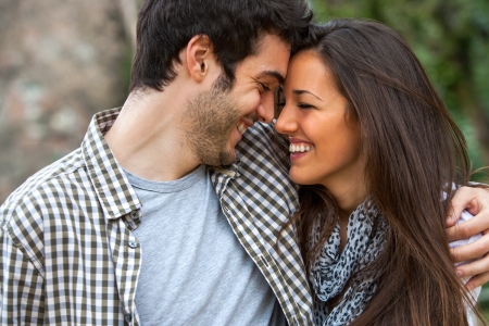 Young couple laughing with heads together outdoors.の写真素材