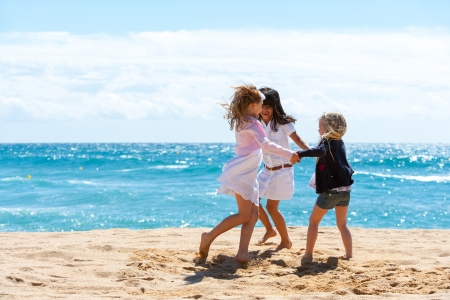 Three young girlfriends playing game on beach.の写真素材