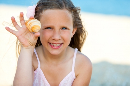Close up portrait of cute girl showing seashell outdoors.の写真素材