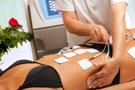 Therapist hands attaching anti aging electrodes on womans body. の写真素材