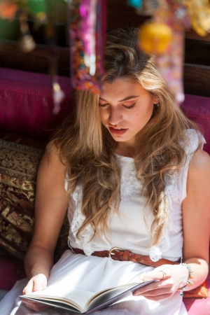 Portrait of attractive girl reading a novel on couch outdoors.の写真素材