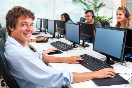 Portrait of smiling male student working on computer with mates.の写真素材