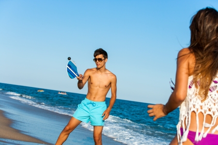 Young couple playing smash ball beach tennis outdoors.の写真素材