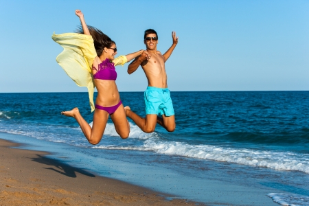 teen couple jumping high on sunny beach.の写真素材