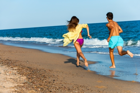 teen couple chasing each other on beach.の写真素材