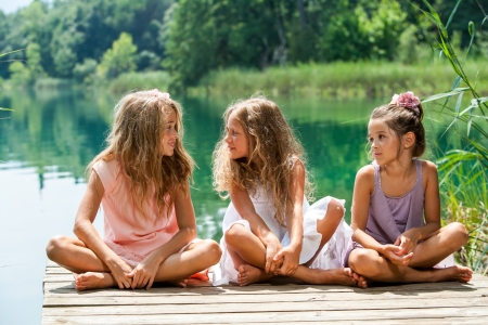 Portrait of young female threesome having conversation on river jetty.の写真素材