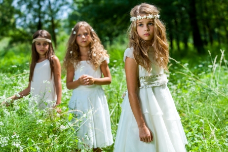 Portrait of three girl friends wearing white dresses in woods.の写真素材