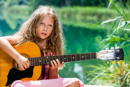 Close up portrait of young guitar student playing spanish guitar at lake.の写真素材