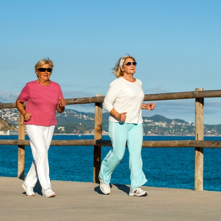 Senior fitness women jogging together at beachfront.の写真素材