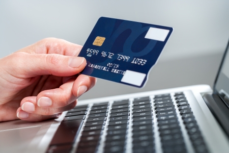 Macro close up of female hand holding credit card on laptop.の写真素材