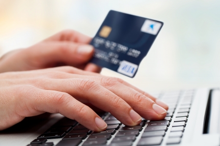 Extreme close up of female hand typing o keyboard with credit card.の写真素材