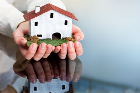 Close up of female hands holding small wooden house.の写真素材