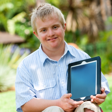 Close up portrait of disabled boy holding blank tablet with copy space outdoors.の写真素材