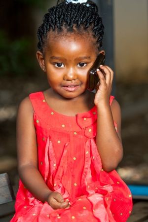 Close up portrait of cute african girl talking on cell phone outdoors.の写真素材