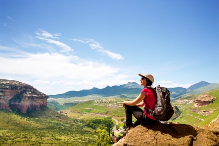 Young female hiker sitting on rock contemplating scenic view.の写真素材