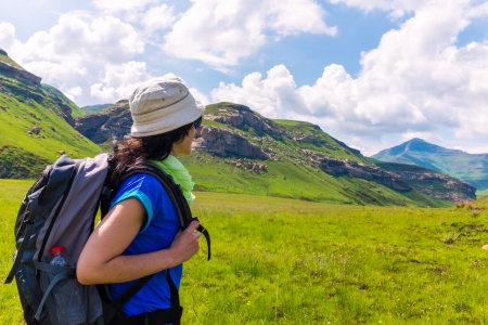 Young female tourist with backpack  walking mountain trail.