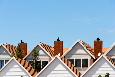 Close up detail of town house rooftops with chimneys against blue shy.の写真素材