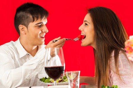 Fun portrait of Young man feeding girlfriend at Romantic dinner.の写真素材