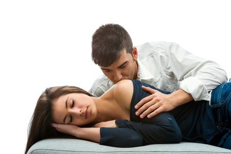 Young man kissing sleepy girl on shoulder.Isolated on white background.の写真素材