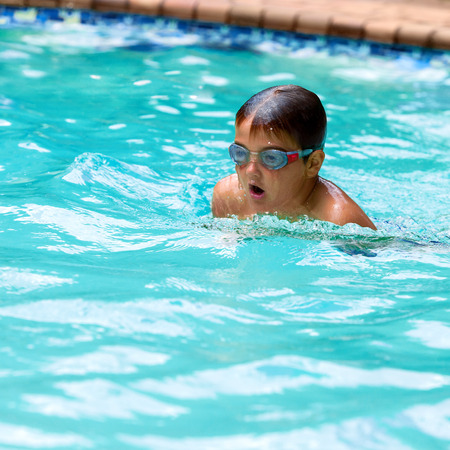 Close up of young boy swimming in outdoor pool.の写真素材