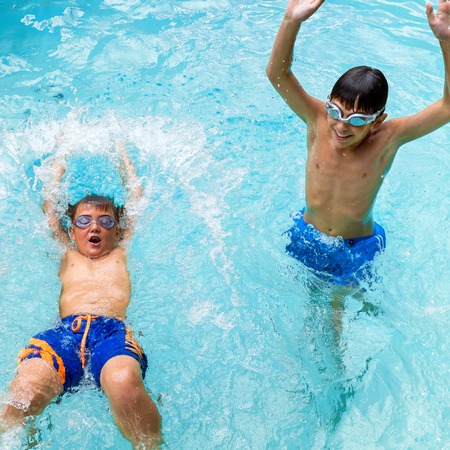 Portrait of two boys splashing water together in pool.の写真素材
