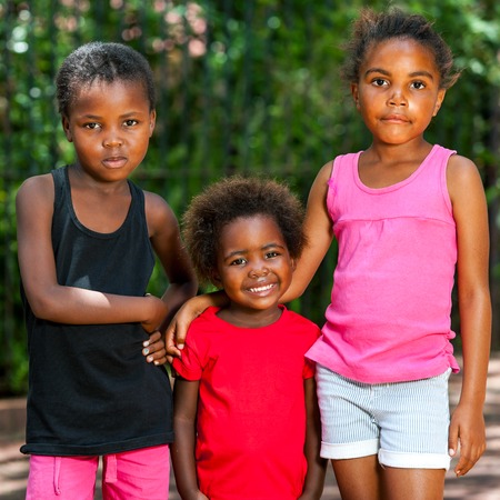 Portrait of three cute young african girls standing together outdoors.の写真素材