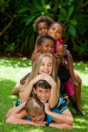 Multiracial children playing together forming human pile in garden.の写真素材