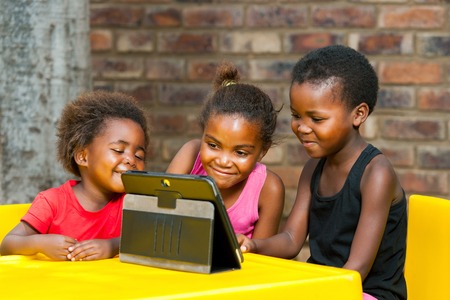 Portrait of three african girls playing leisure games on tablet.の写真素材