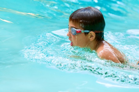 Close up of young boy swimming in pool.の写真素材