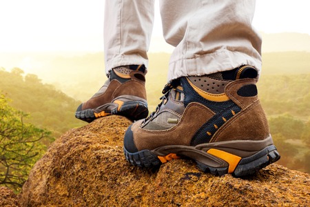 Macro close up of female hiker boots on rocks at sunrise.の写真素材