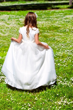Young girl in white dress walking in flower field.の写真素材