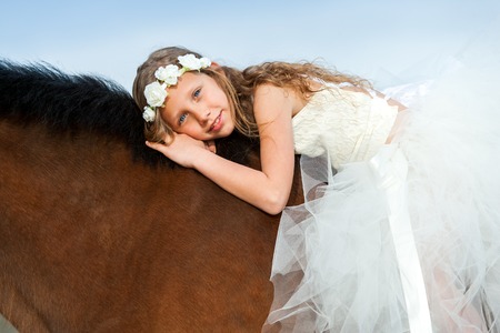 Close up portrait of girl with flower headband laying on horseback.の写真素材