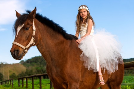 Close up portrait of cute girl with flower head band on horse back outdoors.の写真素材