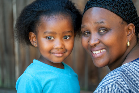 Face shot of little African girl with mom outdoors.の写真素材