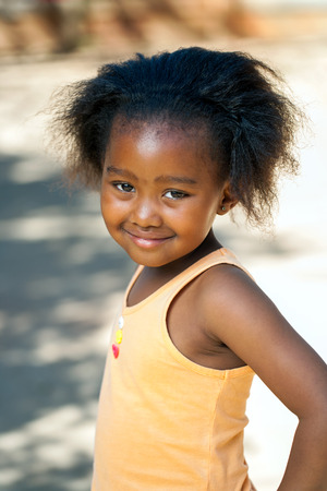 Portrait of cute African youngster in orange vest outdoors.の写真素材