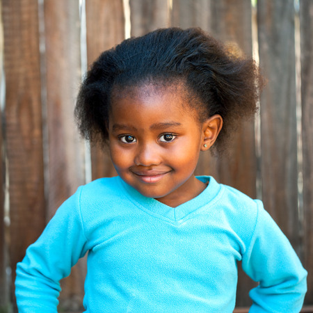 Little African girl wearing blue top outdoors.の写真素材