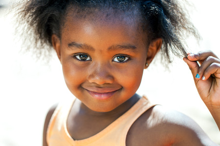 Close up face shot of cute African girl touching hair.の写真素材