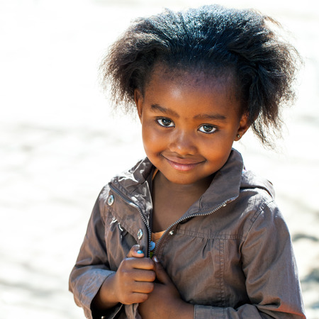Portrait of Little African girl in brown jacket outdoors.の写真素材