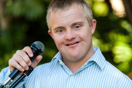 Close up portrait of handicapped boy holding microphone outdoorsの写真素材
