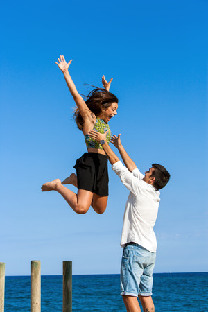 Young man catching girlfriend in air at ses side.の写真素材