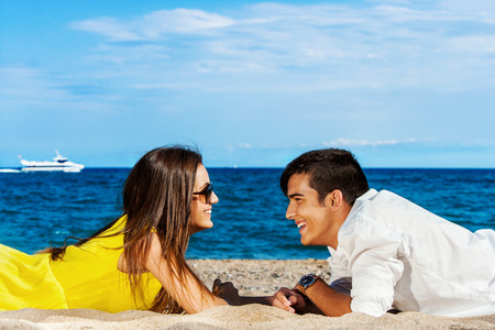 Close up portrait of  Young laying on beach facing each other.の写真素材