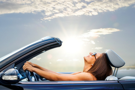 Portrait of Young girl driving cabriolet at sunset.