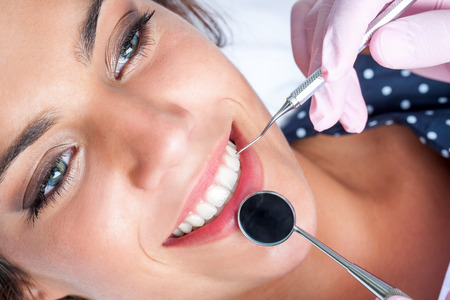 Macro close up of Dentist hands working attractive female teeth.の写真素材