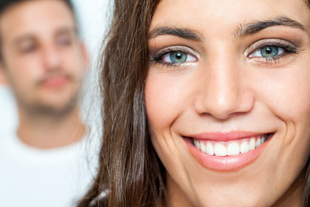 Close up Facial portrait of attractive girl with toothy smile and boy in background.の写真素材