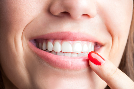 Extreme close up of woman pointing with finger at healthy teeth.の写真素材