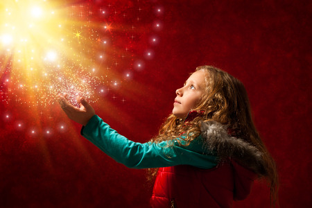 Conceptual portrait of cute young girl touching the stars against reddish galaxy background.の写真素材